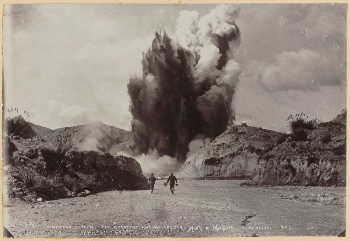 A massive geyser erupting against a hilly horizon. Two small figures are seen in the foreground.