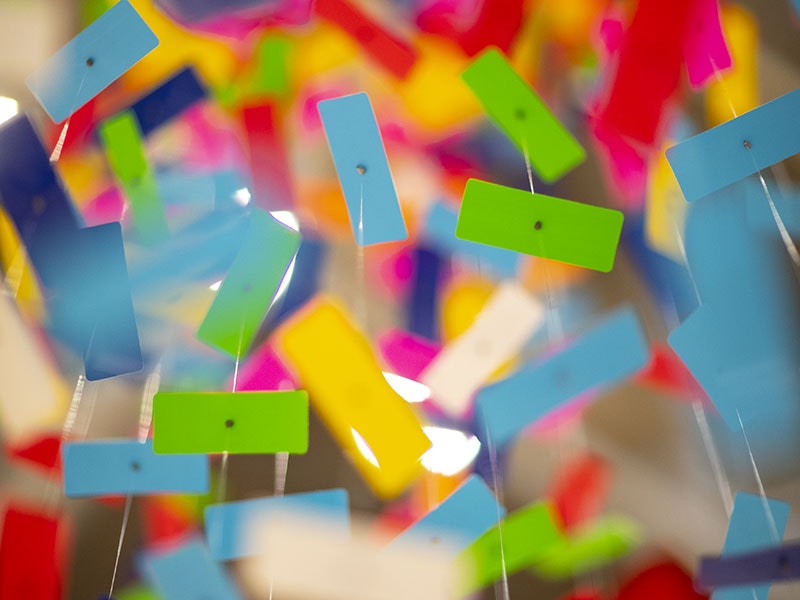 An extreme close-up of brightly-coloured pieces of plastic suspended from the ceiling