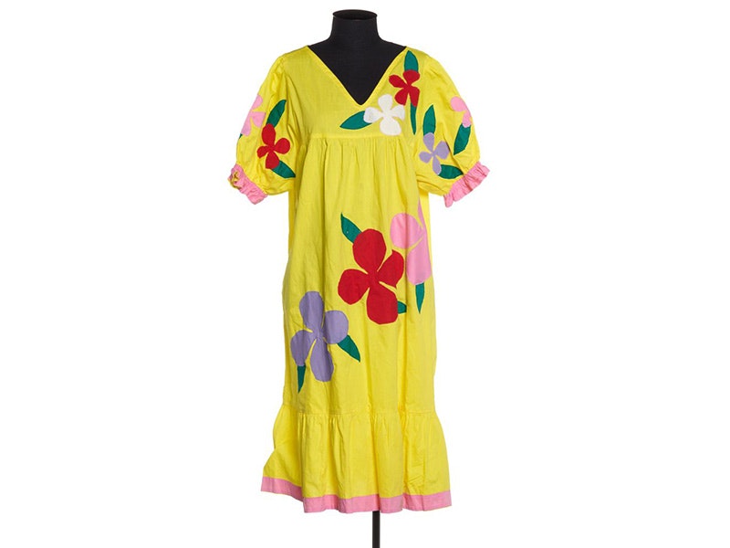 A yellow dress with large red flowers on a clothmaker's dummy