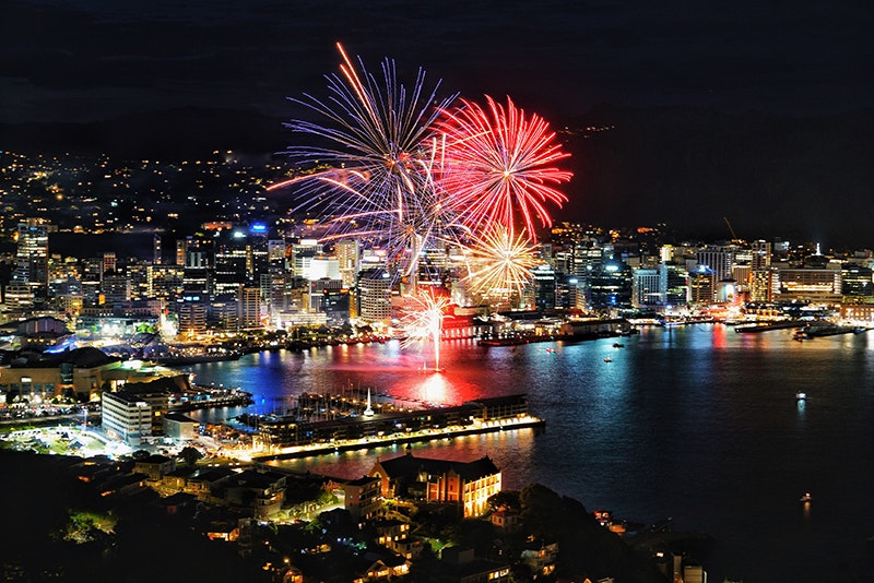 Photo by Jun Yamog, courtesy of Asian Events Trust A night-time photograph of Wellington city with large fireworks exploding over the harbour.