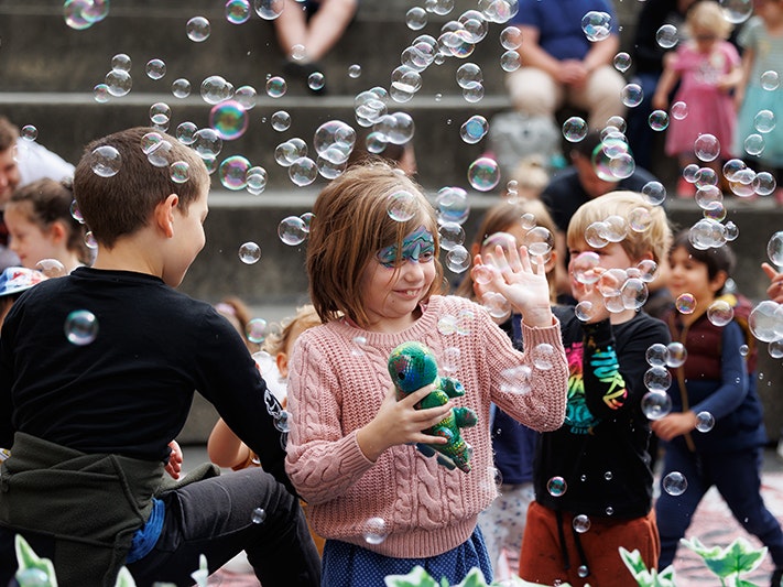 Fossil Finders Whānau Day 2024, Photo by Jo Moore. Te Papa (253238) Kids outside with painted faces and bubbles all around them.