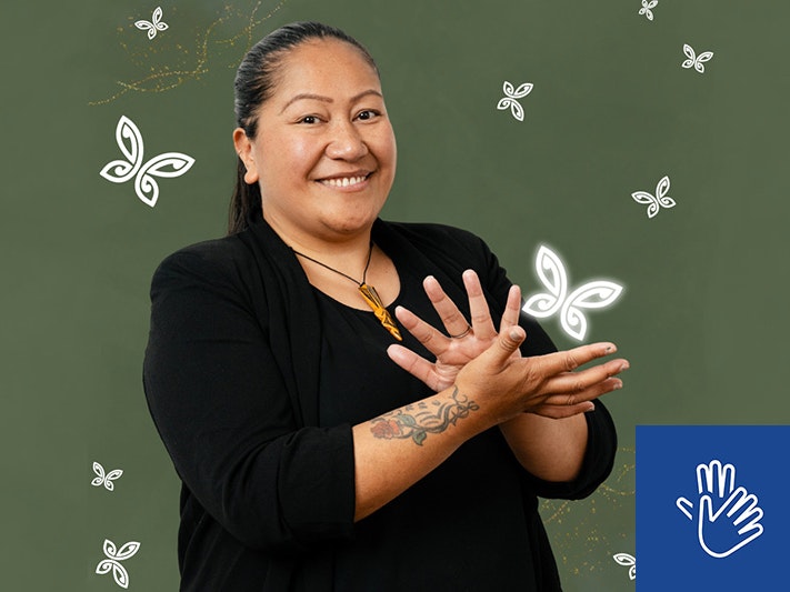 NZSL Awards night. Photo courtesy of NZSL Board A woman is using her hands to say sign language and smiling at the camera.