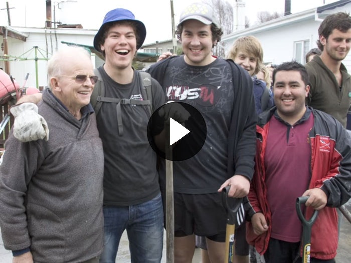 Still from the video 'The Silt Worms: Origins of the Student Volunteer Army'. Te Papa Student volunteers smile with other members on the public