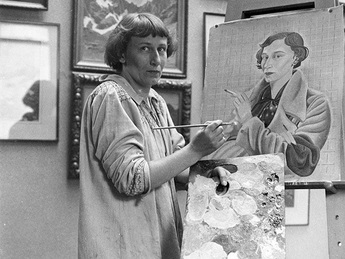 Rita Angus painting Self portrait, 1936-1937, by Jean Bertram. Te Papa (CA000242/001/0003) Rita Angus looks towards the photographer in a portrait of her painting herself
