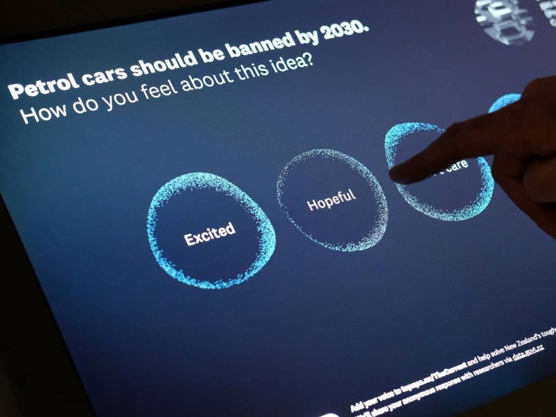 The Current, 2019. Te Papa Visitor plays with a digital screen on it the words says 'Petrol cars should be banned by 2030. How do you feel about this idea?'