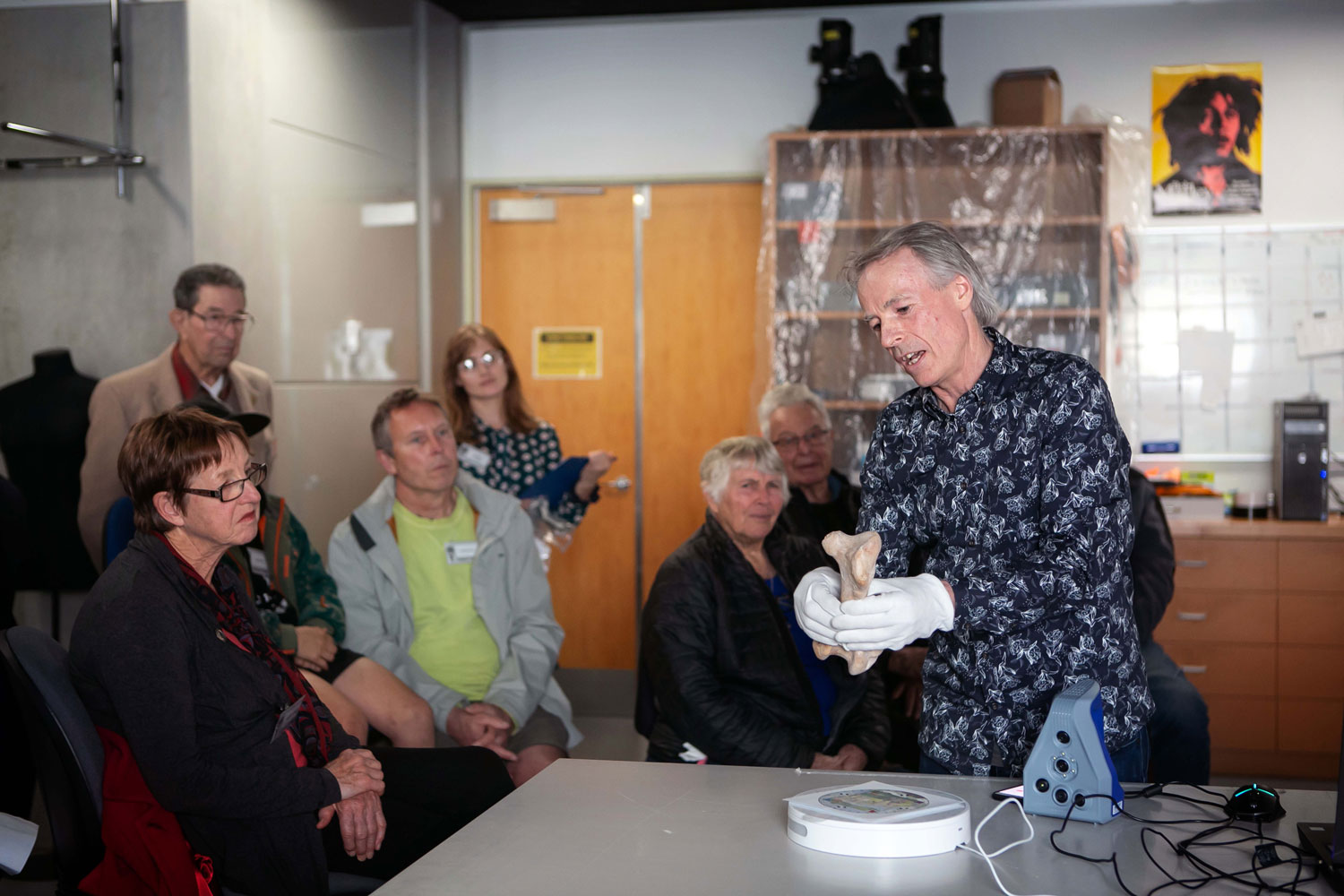 A man in front of a crowd holds a moa bone