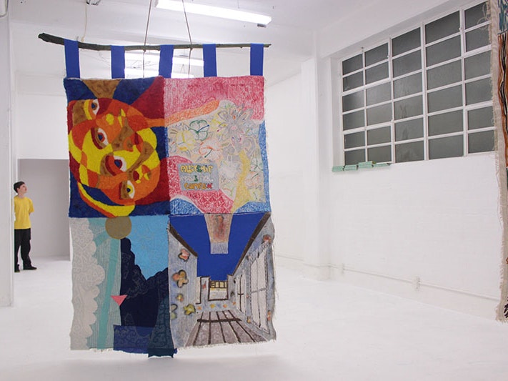 View of Owen Connors’s exhibition SISSYMANCY! at play_station, Wellington, 2019. Photo by Pippy McClenaghan, courtesy of Owen Connors A large quilt hangs from the ceiling of the play_station gallery. It is an almost empty, white space. Part of another quilt can be seen hanging to the right of the frame