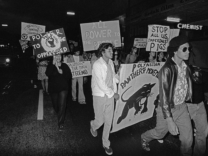 Polynesian Panthers protestors in central Auckland during the Soledad Brothers solidarity march on the US Consulate, 3 March 1972. © John Miller, 1972 A group of people march in a line holding placards
