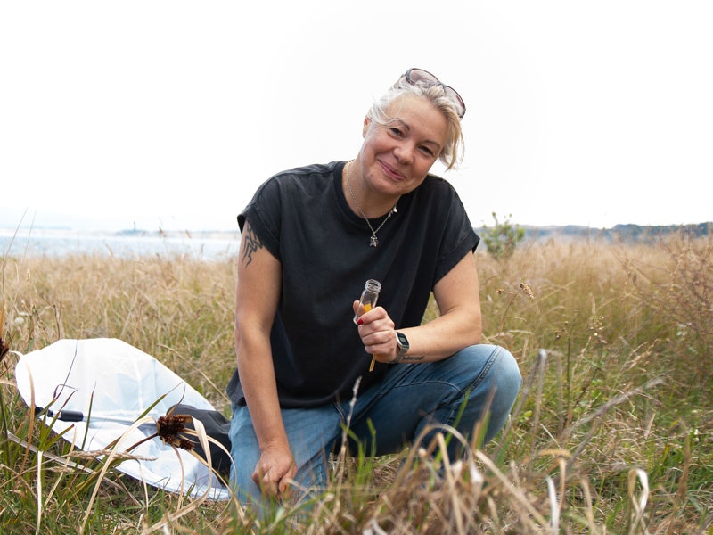 Julia Kaspar, 2020. Photo by Rachael Hockridge. Te Papa Julia kneeling in the grass, she has a net by her side