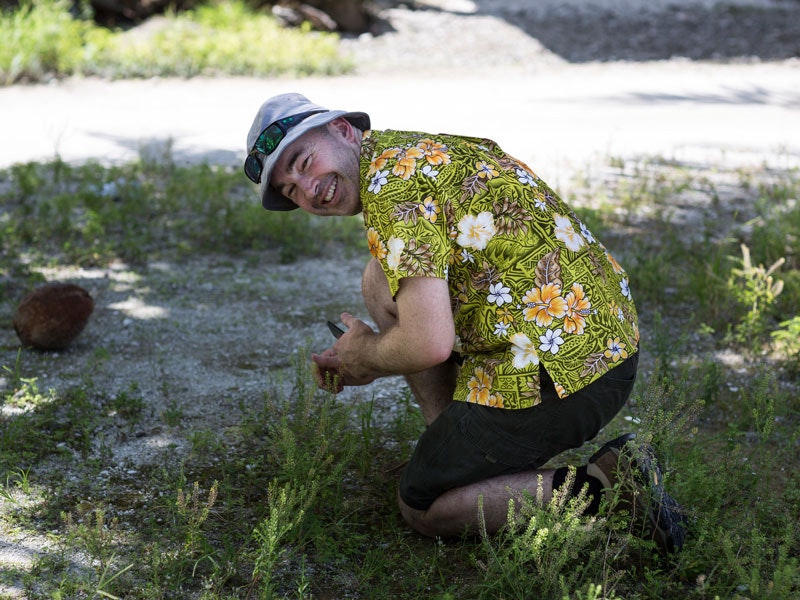 Man in a Hawaiian shirt looking at plants and smiling