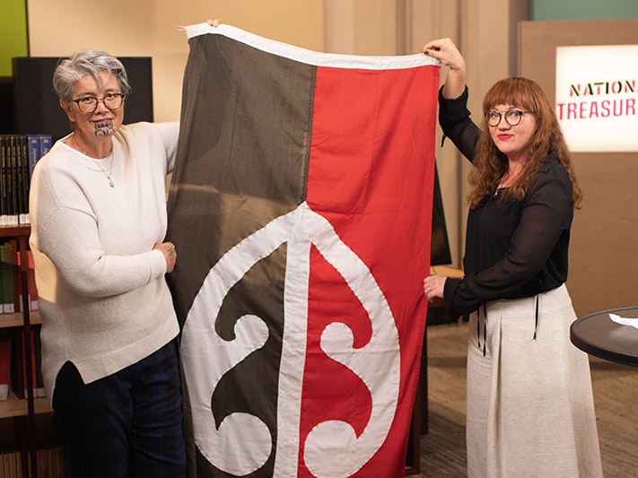 Sharon Hawke and Matariki Williams holding a flag from Bastion Point. Photo courtesy of Hawke Whānau Trust, TVNZ, and Pango Productions national-treasures-800x533.jpg