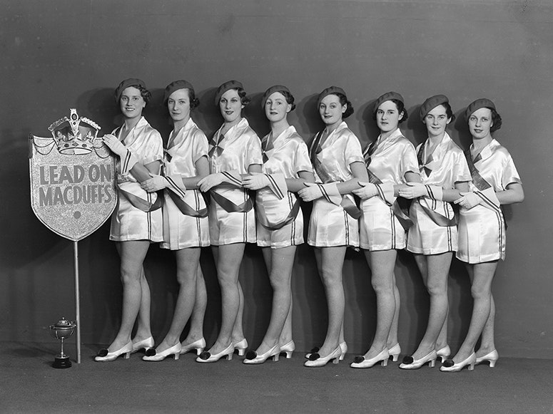 McDuff Marching Girls, 1937, Wellington, by Spencer Digby Studios. Spencer Digby / Ronald D Woolf Collection. Gift of Ronald Woolf, 1975. Te Papa (C.021135) Black and white photo of women lined up beside a trophy in uniform