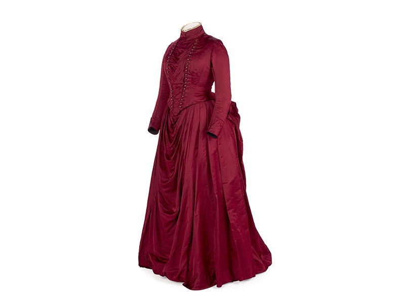 Bustle dress, silk satin with cotton lining, whale bone, and metal fastenings, James Spence and Company, manufacturer(s); 1885/1890; London. Gift of Mrs. M. Hely, 1979. Te Papa (PC001941) A red 1880s silk dress with a bustle on a white background