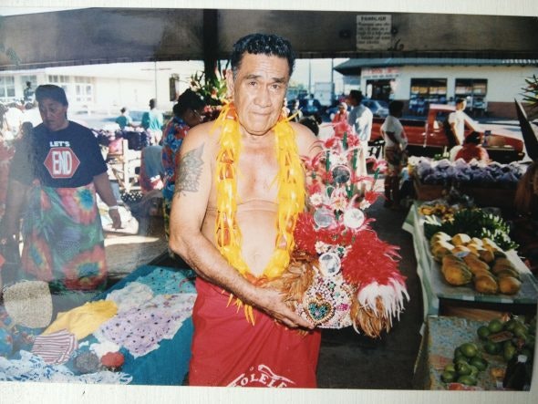 The maketi manager in 1994 – Laulua Mailata of Vaimoso A man standing in a colourful market stall holding a feathered headdress