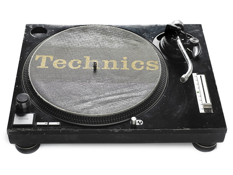 Technics 1200 Turntable, 1989-1990, United States, by Technics. Purchased 2000. CC BY-NC-ND 4.0. Te Papa (GH009266)  a black and grey record turntable on a white background