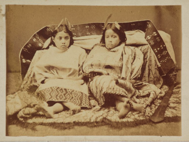 Two Maori girls (The Misses Swanson?), 1869-76, New Zealand. American Photographic Company (Auckland). Purchased 1999 with New Zealand Lottery Grants Board funds. Te Papa A sepia photo of two girls in a photography studio looking at the camera