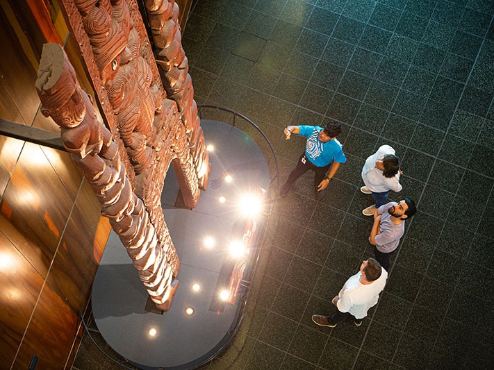 Visitors on a tour of Te Papa, 2020. Photo by Jeff McEwan. Te Papa A Te Papa host points at a waharoa (a gateway) on display while visitors look on