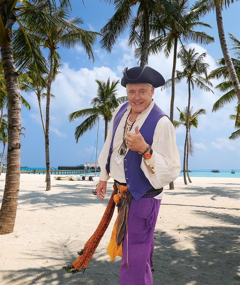 A man in a pirate outfit is photoshopped onto a beach