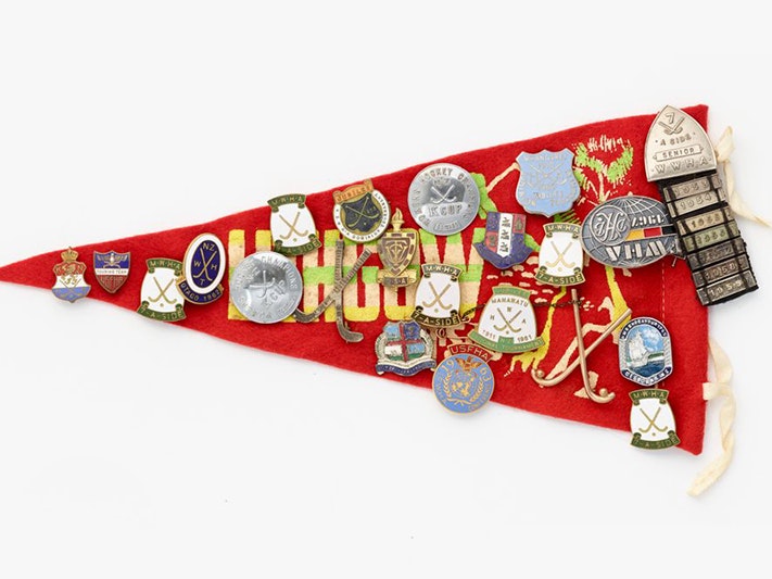 Souvenir pennant with badges, Unknown; manufacturer(s); 1950s–1960s. Gift of Enoka William John Stratton, in memory of Elva Marama Love (née Enoka), 2009. Te Papa (GH016352) A red felt triangle flag covered in metal and enamel badges for sport