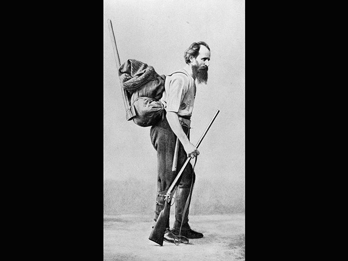 Andreas Reischek. Making New Zealand: Negatives and prints from the Making New Zealand Centennial collection. Ref: MNZ-0300-1/4-F. Alexander Turnbull Library, Wellington, New Zealand. /records/23050601 An old photo showing a bearded man carrying a pack and a rifle