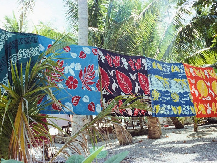 Glenn Jowitt, Tokelau, 1981. Gift of Glenn Jowitt Estate, 2015. Te Papa (E.007346) Several brightly coloured sheets are hanging on a washing line on beach with coconut  trees
