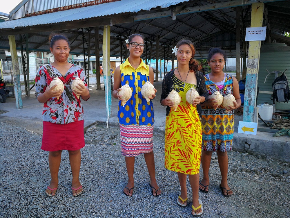 Tokelau locals, 2017. Photo by Michael O’Neill. Te Papa Four young girls are standing and all are holding a coconut in each hand