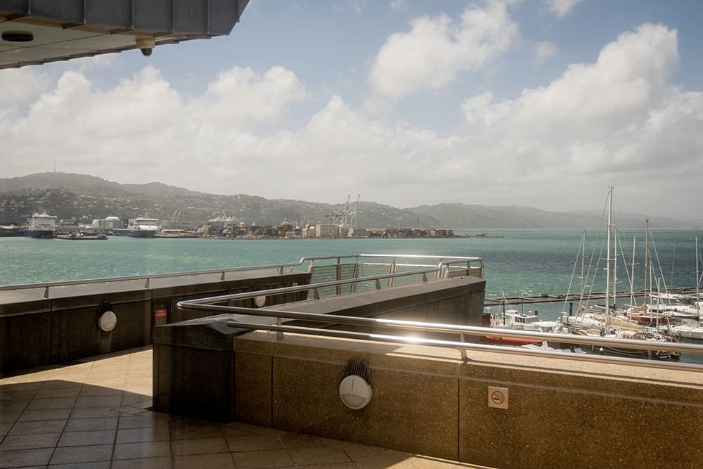 A lookout-style balcony on a building. There is a harbour in the background.