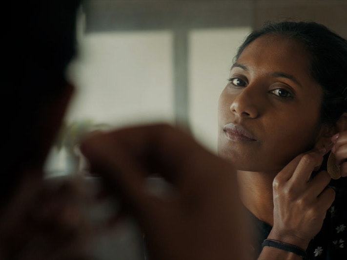 Still from ‘Healing doesn’t just happen in one mode’: reconsidering what ‘therapy’ looks like, 2023. Photo by Julie Zhu Photo of a woman looking into mirror, putting on an earring.