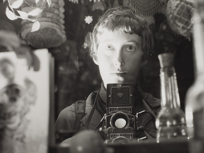 Ans Westra, Self portrait, 1964, black and white photograph, gelatin silver print. Te Papa (O.042837) A woman with a camera is taking a self portrait in a mirror.
