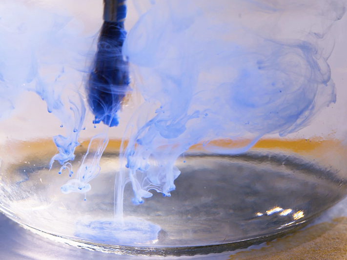 Still from A Painter's Journey. Te Papa A paintbrush in a glass of water and swirling blue paint