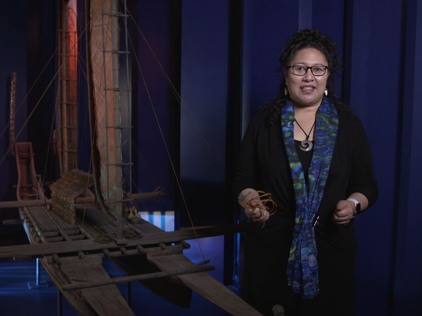 A still from Raranga Matahiko 6a and 6b. Te Papa A woman standing inside in front of a canoe