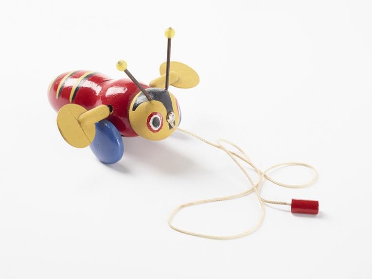 Toy, 'Buzzy Bee', circa 1943, Auckland, by H.E. Ramsey Limited, Maurice Schlesinger. Gift of Judith Clearwater on behalf of Robin Clearwater, 2012. CC BY-NC-ND 4.0. Te Papa (GH022590) A wooden toy on a string, it is a brightly coloured bee with wings that make clacking sounds as it is pulled along.