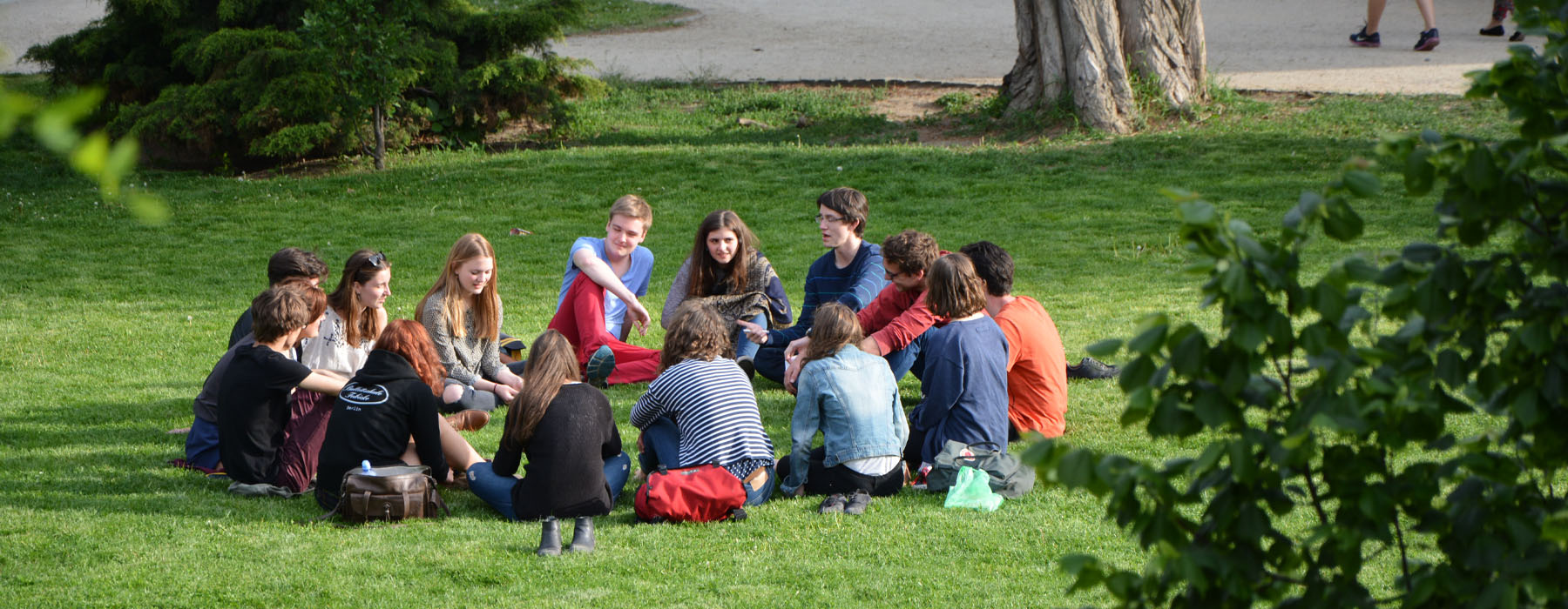Group of young people sitting in a circle in a park