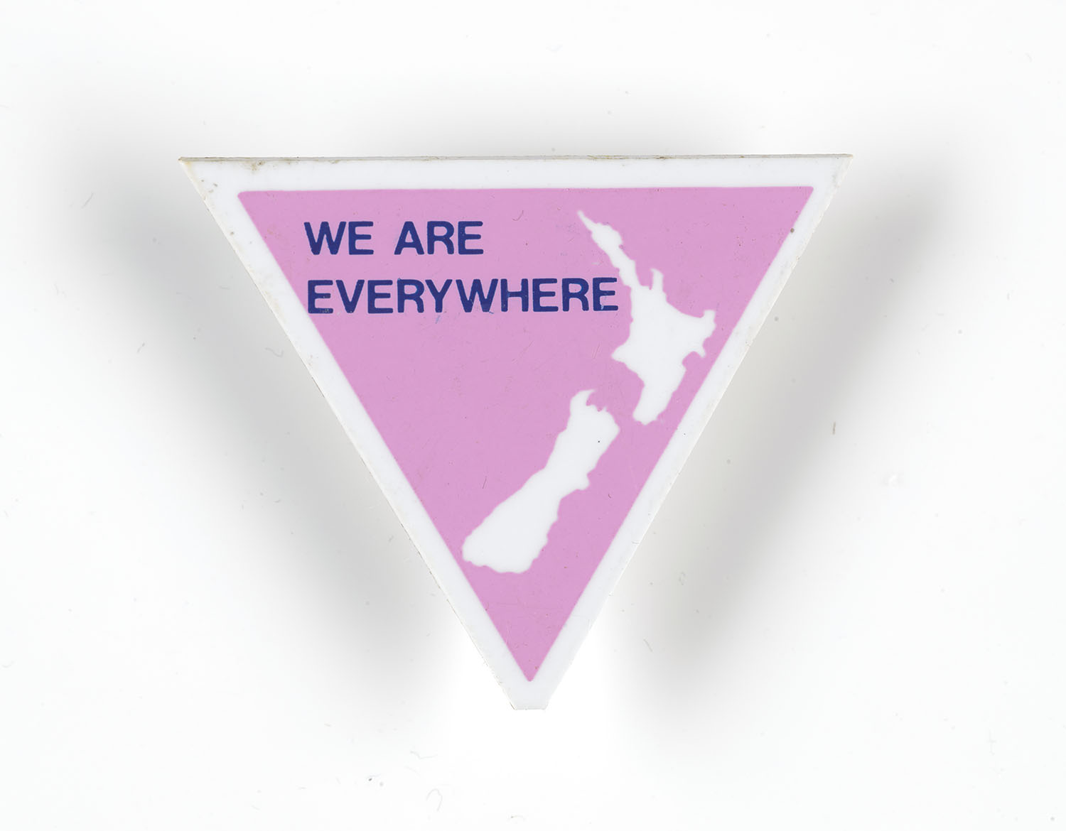 Pink triangle badge with a white silhouette of New Zealand and the words, in purple, “We are everywhere”