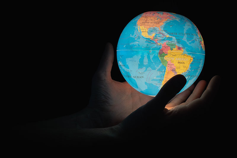 Photo of hands holding a small globe which is illuminated from the inside