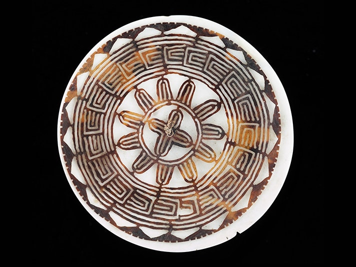 Kapkap, circa 1890, Solomon Islands, maker unknown. Augustus Hamilton Collection. Purchased 1914. CC BY-NC-ND 4.0. Te Papa (FE000043) A round disc made of turtle shell that has been carved into a pattern.