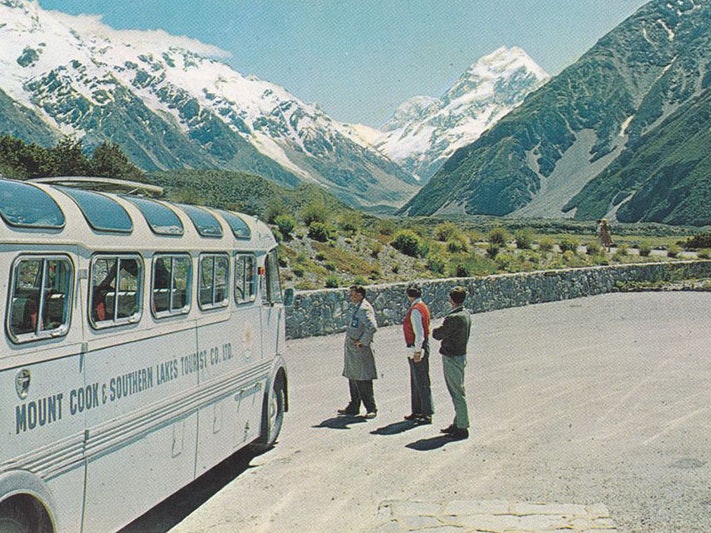 Mount Cook and bus, 1960s, by Gladys Goodall. Te Papa (PS.003574) View of Mount Cook from a carpark. A bus can be seen to the left and three people on the right stand looking at the mountain