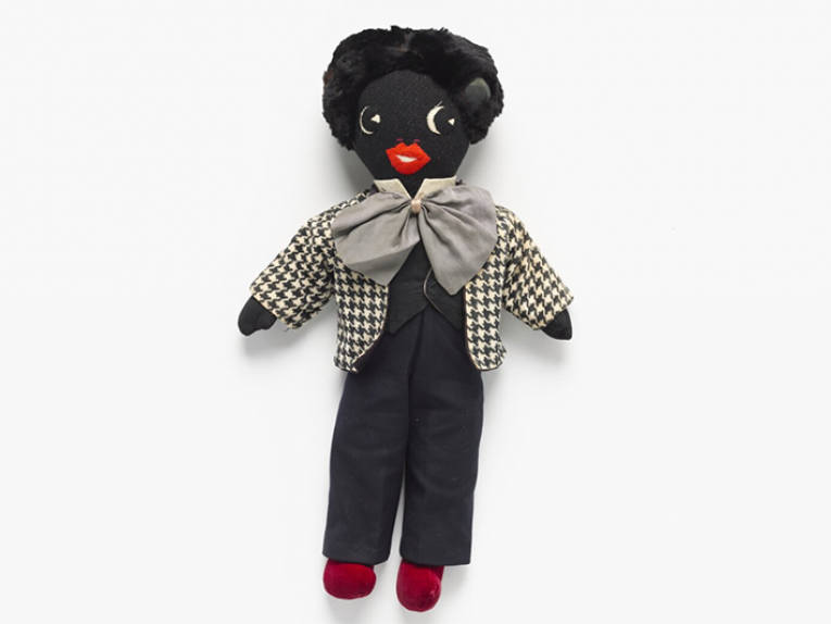 Golliwog, Unknown; maker/artist; circa 1962; New Zealand. Gift of the Barkman family, 2015. Te Papa (GH018095/1-3) A doll on a light grey background. The doll is dark black and called a golliwog.