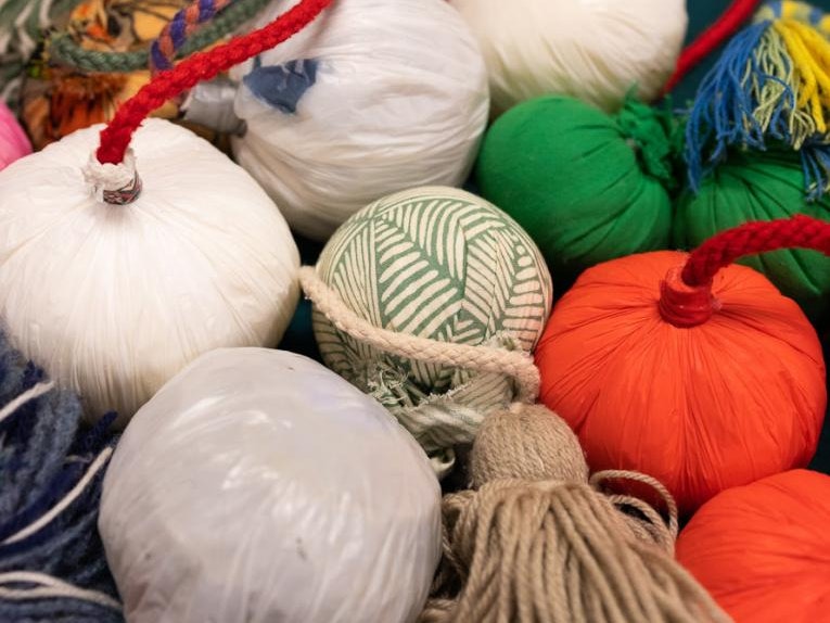 Contemporary Poi, Poi of Te Āteanui Puoro Tira, 2023, plastic, fabric, wool. Photo courtesy of Sam Palmer A group of brightly-coloured round balls with cords attached all clustered together.