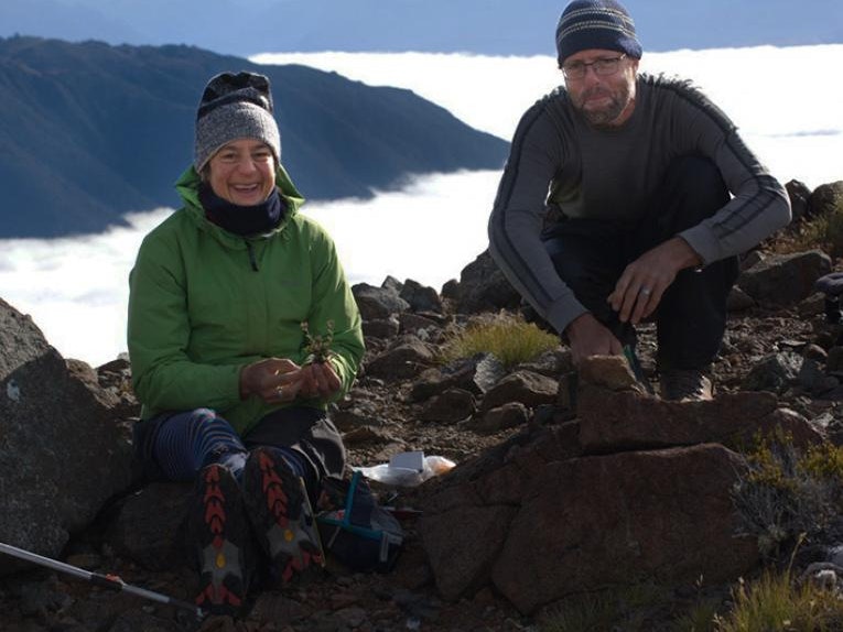 fiordland-mike-photo-of-heidi-and-ant tile Two people in hiking clothes are sitting on top of a mountain.