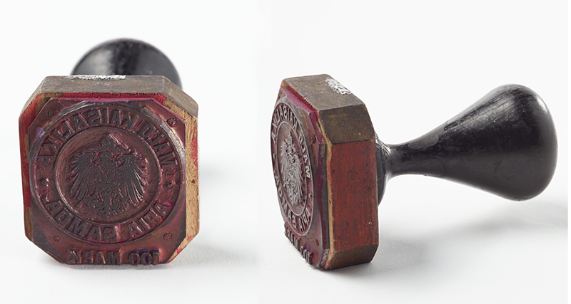 Two views of the same rubber stamp with a black wooden handle.