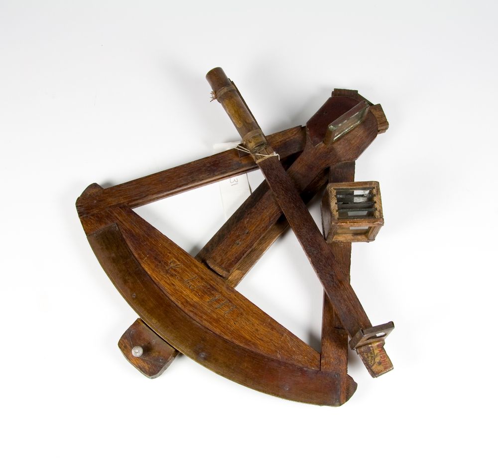 A wooden sextant with brass attachments on a white background