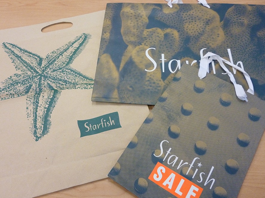 Starfish retail shopping bags, 1993-2013, by Laurie Foon, The Carry Bag Company. Gift of Laurie Foon, Starfish, 2014. © Te Papa. CC BY-NC-ND 4.0. Te Papa (CA001205/003/0001) A photo of a cotton bag, and two paper bags with Starfish logo and promotion on them.