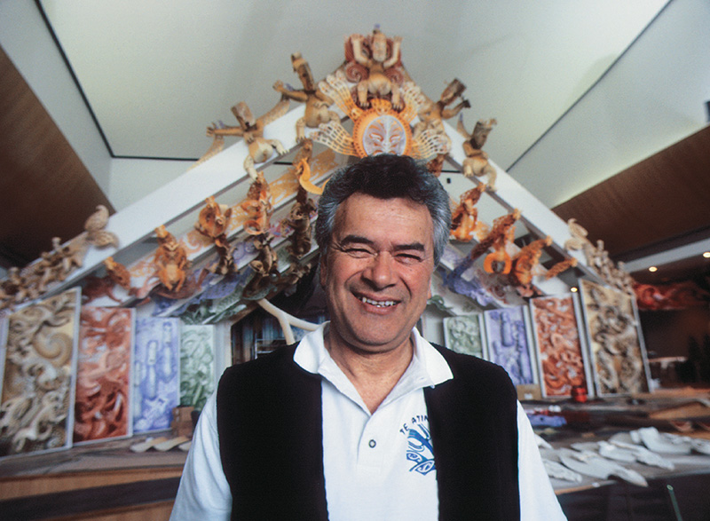 Head and shoulders of a man standing in front of a whare.