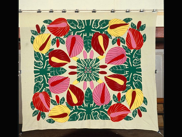 Tivaevae tataura, anthuriums pattern, by Norma Iro, photo by John Daley; photographer; about 1992; Cook Islands. Gift of John Daley, 2012. Te Papa (F.012398) A large piece of material with bright patterns of flowers and leaves.
