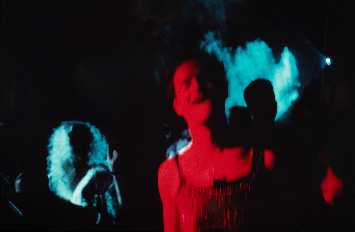 A photo of someone dancing or singing at a darkly lit space with red and blue lighting.