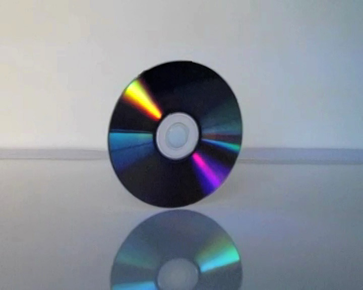 A disk standing on its edge with it reflecting on a shining surface.
