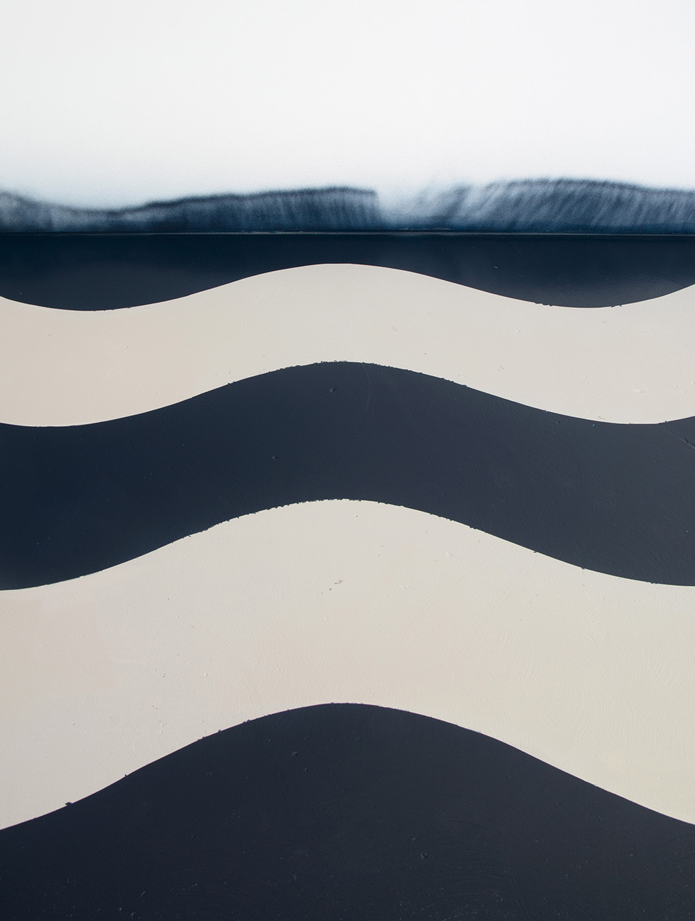 A dark blue and cream set of wavy stripes with the top stripe looking like a misty wave crashing over.