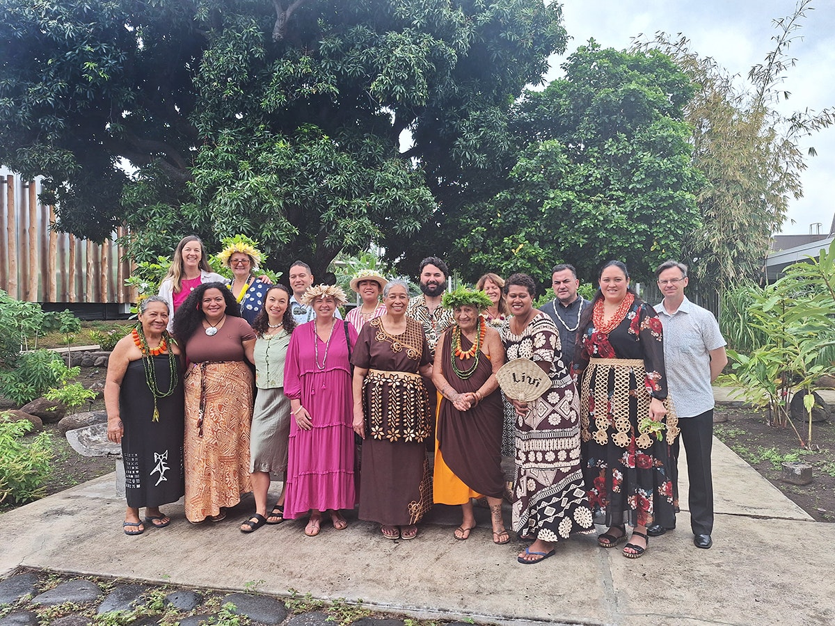 Participants in the ‘Ahu: ngā wairua o Hina (‘Ahu- the spirit of Hina) in the gardens at Te Fare Iamanaha – Musée de Tahiti et des Îles. Photo by Te Papa A group of people in colourful and patterned clothing are standing and smiling at the camera.