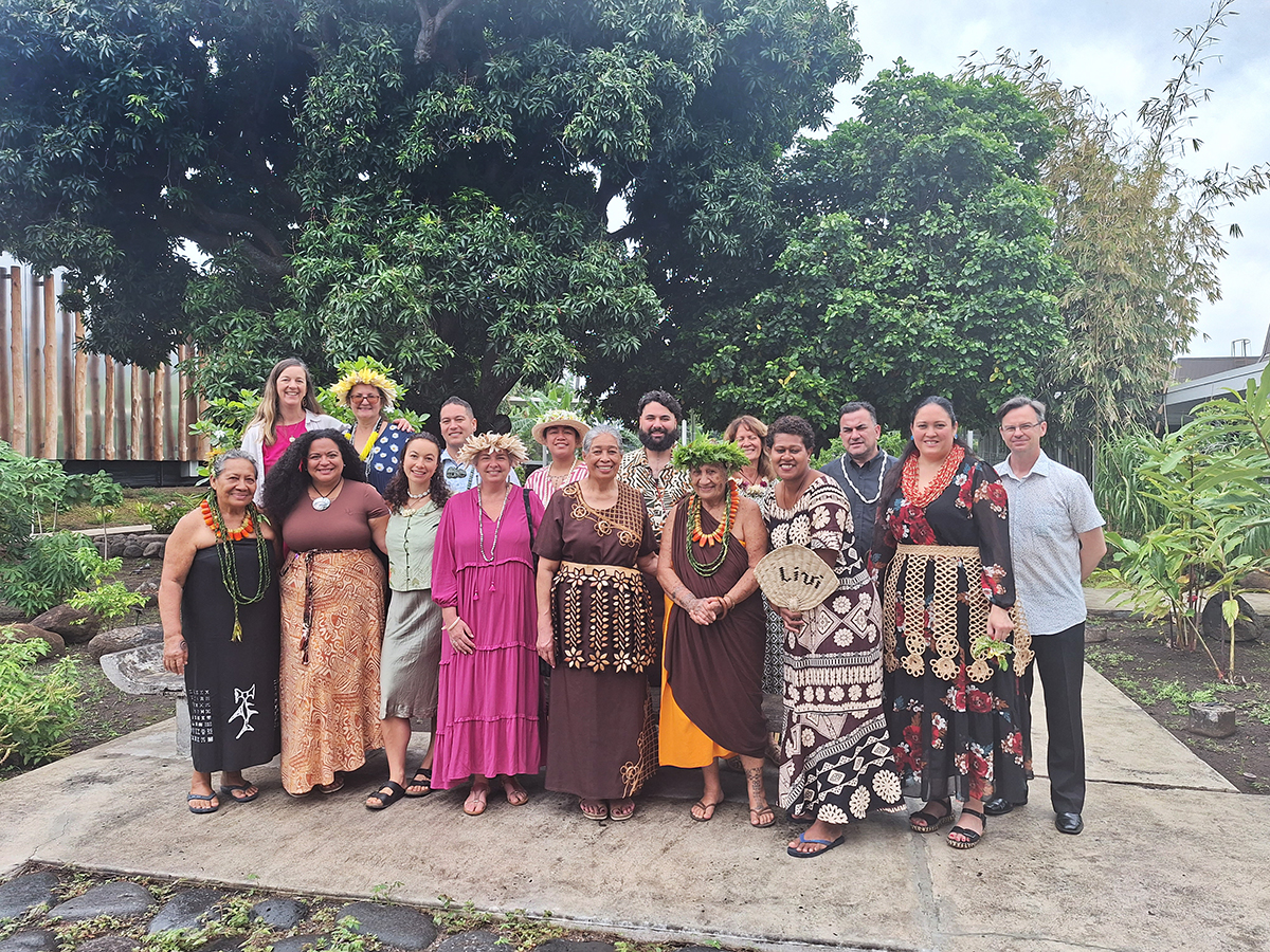 A group of people in colourful and patterned clothing are standing and smiling at the camera.